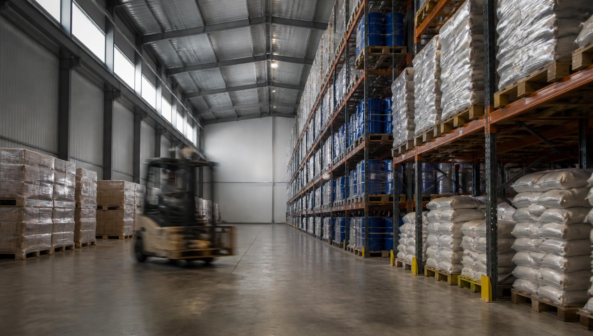 Interior of a CRC third-party warehouse with racked pallets and a forklift in motion